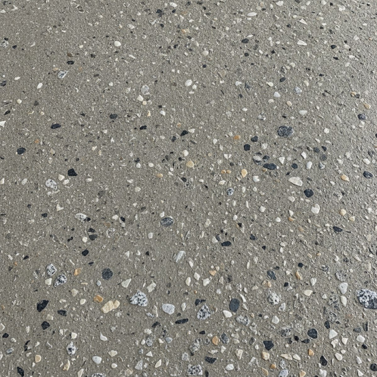 Close-up of a concrete floor surface after diamond grinding, exposing the aggregate in a rough prepared texture